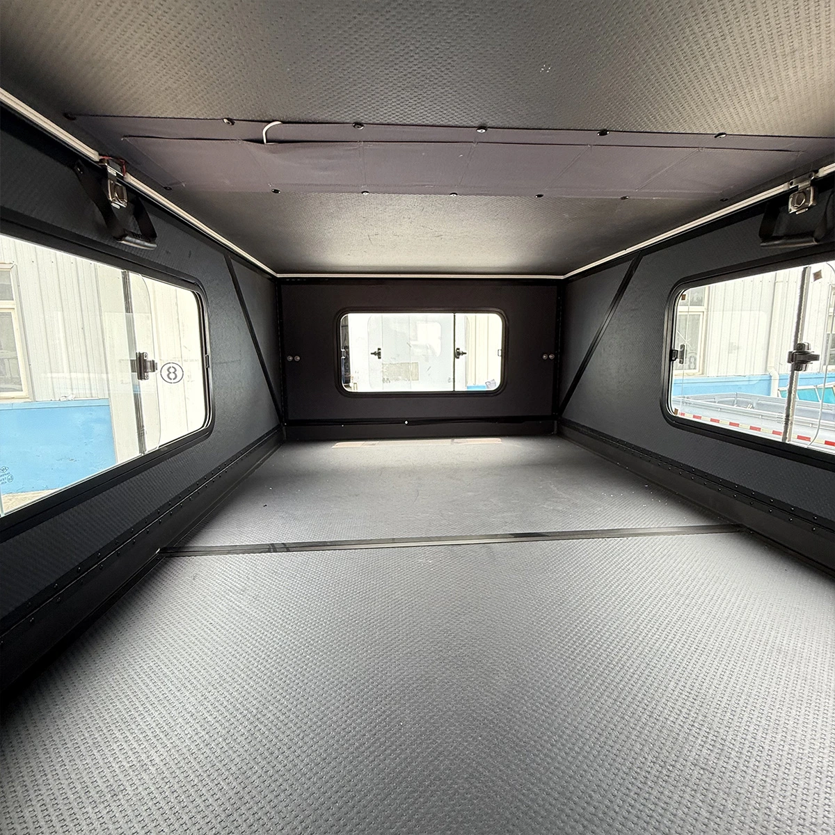 L'intérieur du KOVR XL1 : la plateforme de couchage pleine largeur, avec des fenêtres sur trois côtés