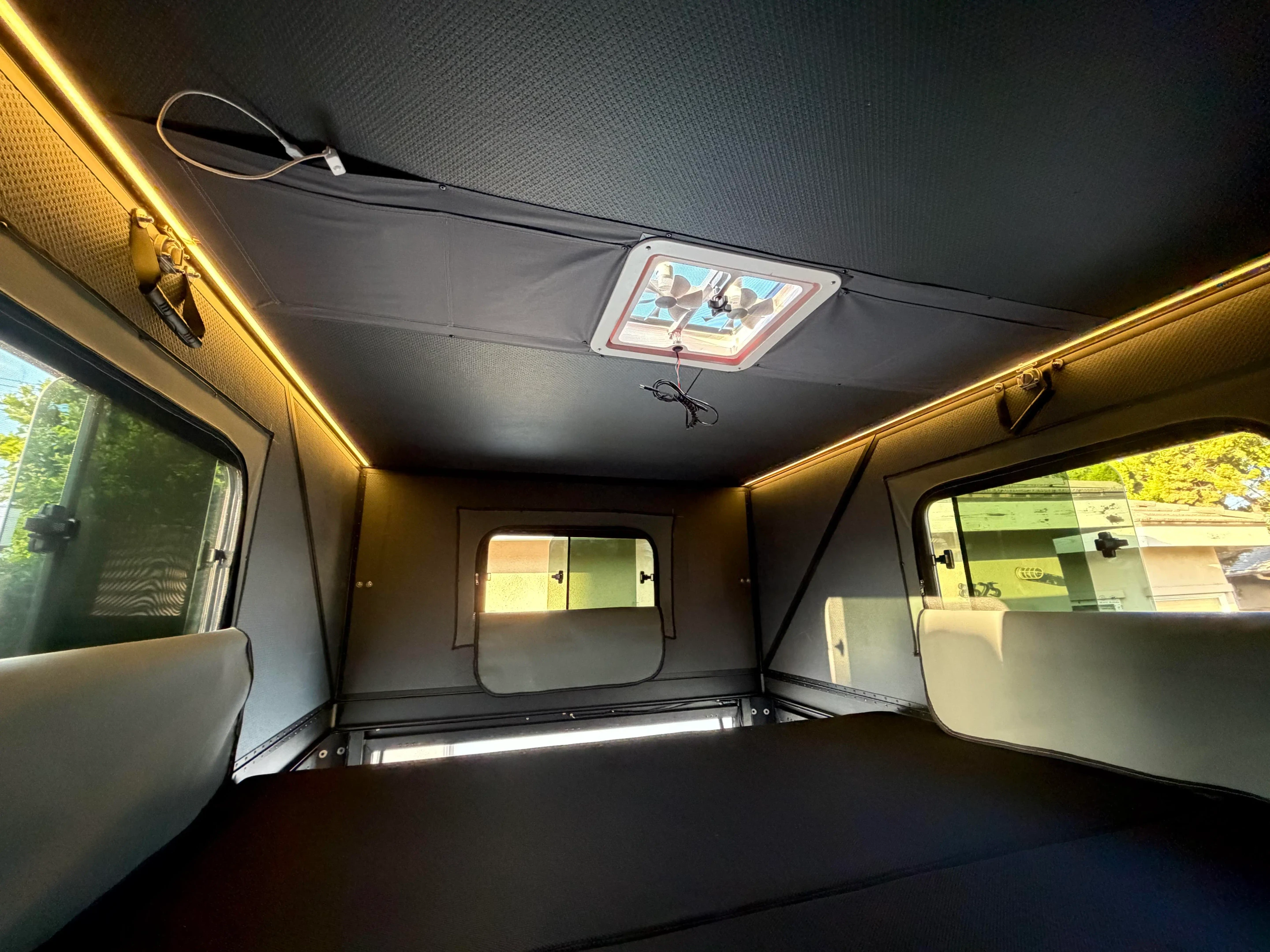 L'intérieur du KOVR XL1 : fenêtres panoramiques sur trois côtés, bandes DEL chaudes le long du toit et ventilateur de plafond au-dessus du matelas