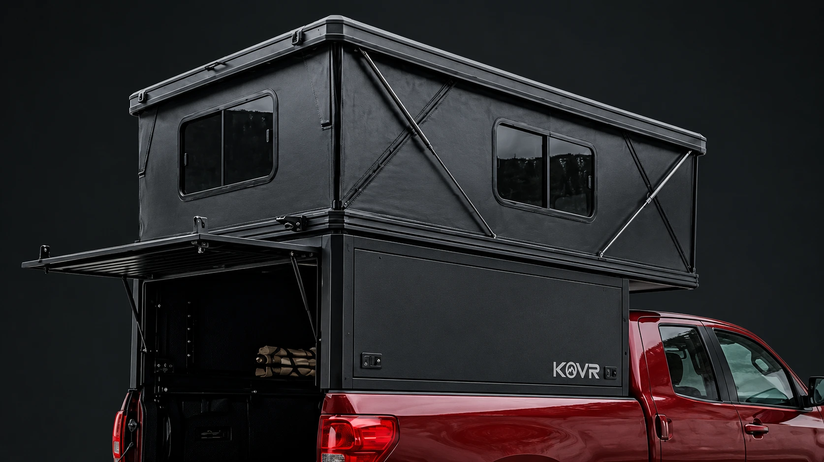 Render of the KOVR S1 on a red pickup: a black pop-up camper sitting flush with the truck bed, rear panel and tailgate open